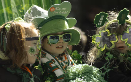 HD PC desktop wallpaper featuring children dressed in festive green attire, sunglasses, and shamrock accessories celebrating St. Patrick's Day.