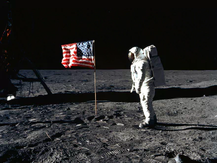 HD desktop wallpaper showing astronaut Neil Armstrong on the moon next to the American flag against a black lunar sky.