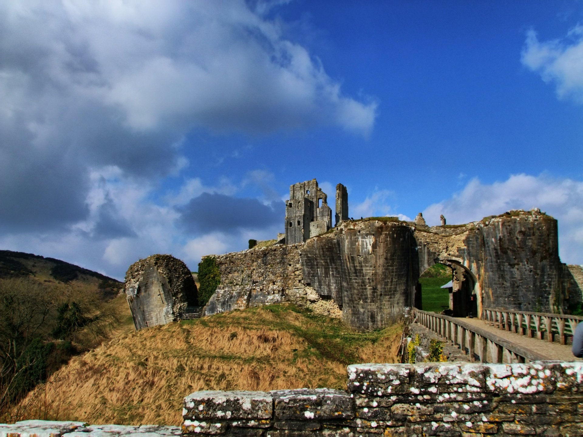 4K Ultra HD PC desktop wallpaper of a man-made castle perched on rocky cliffs, linked by a stone bridge under a dramatic blue sky.