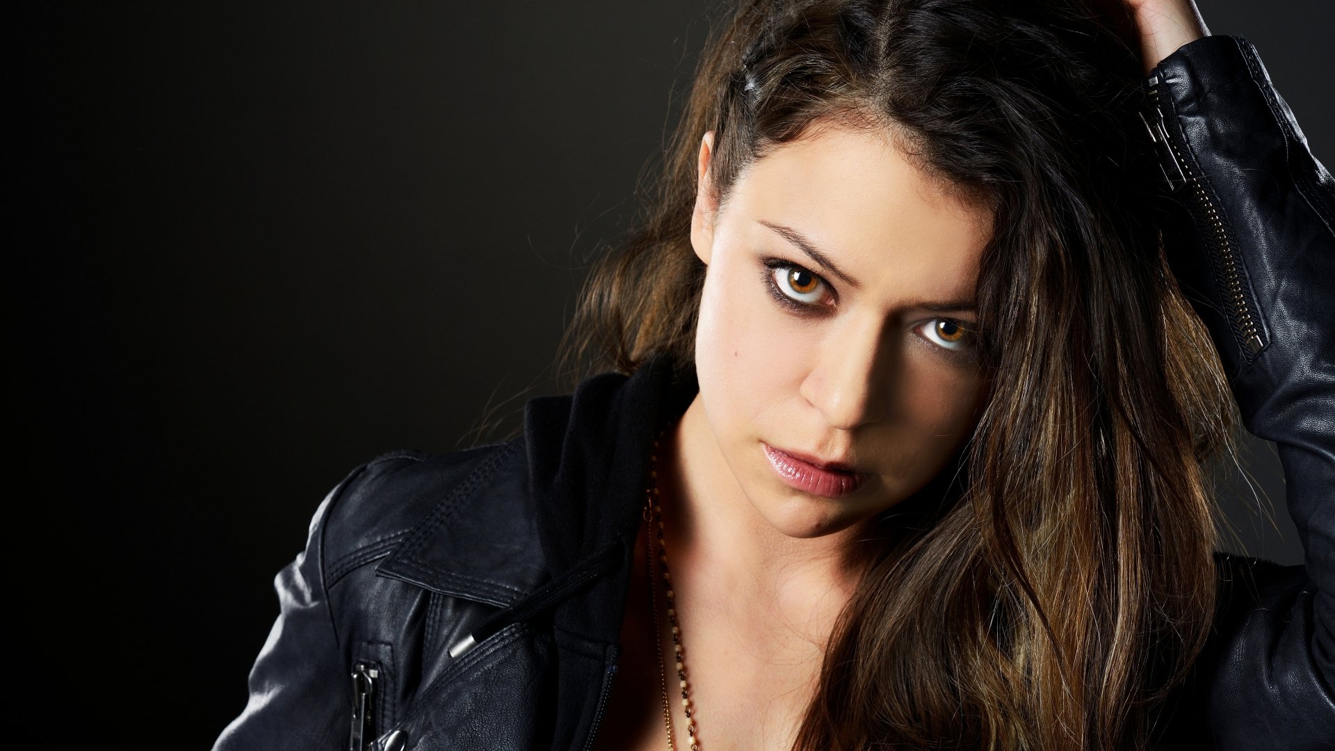 Orphan Black TV show 5K Ultra HD desktop wallpaper: close-up of a brooding young woman in a leather jacket, intense direct gaze against a dark background.