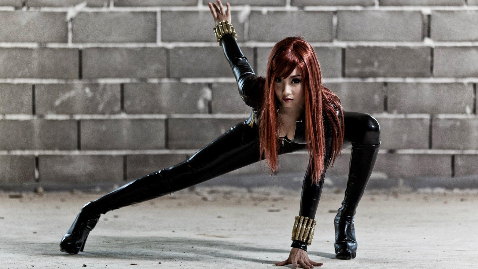 A woman in striking cosplay poses dynamically against a textured wall, showcasing her outfit. This high-definition image serves as an engaging desktop wallpaper or background.