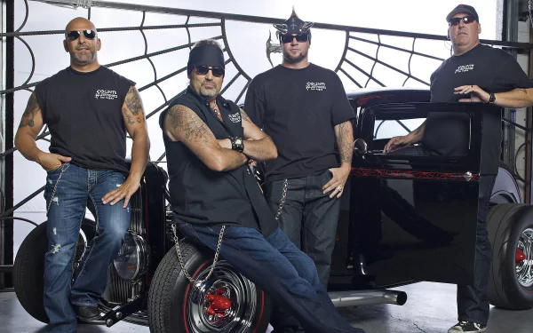 HD desktop wallpaper featuring the cast of the TV show Counting Cars posing with a custom vintage hot rod in a garage setting.