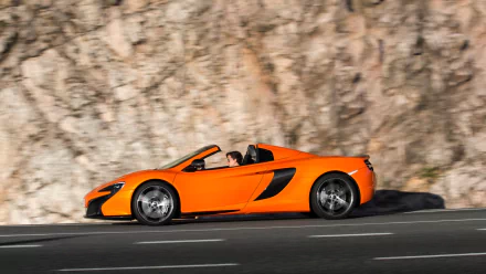Orange McLaren 650S Spider supercar driving past a rocky cliff, vivid orange car on the road — HD PC desktop wallpaper and background