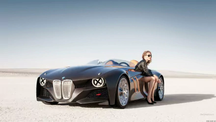 A stylish woman in sunglasses casually sits next to a sleek black sports car on a sandy landscape, showcasing a captivating blend of elegance and automotive design.