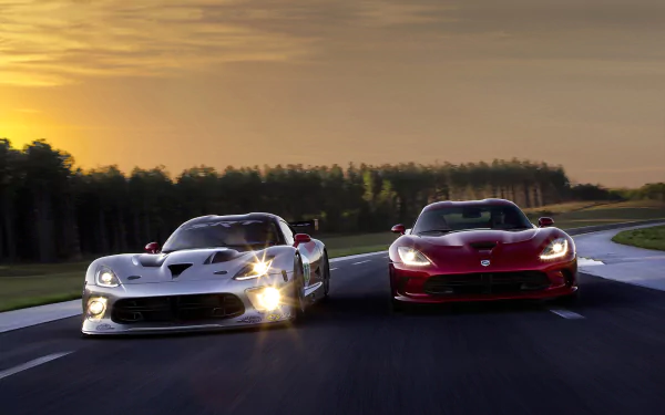 Two Dodge Viper GTS-R race cars, one white and one red, speed side by side on a track at sunset in this HD PC desktop wallpaper.