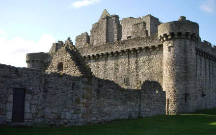 HD PC desktop wallpaper/background of Craigmillar Castle: a man-made medieval stone fortress with sunlit battlements and outer walls against a blue sky.