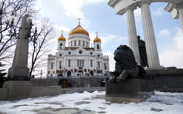 Religious view of the Cathedral of Christ the Saviour with golden domes and a foreground lion statue on a snowy square — HD PC desktop wallpaper/background.
