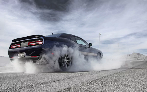 HD wallpaper featuring a Dodge Challenger SRT Hellcat burning rubber against a scenic, cloudy background. The powerful vehicle dominates the image, capturing the essence of speed and performance.