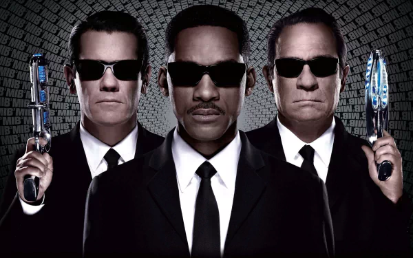 HD PC desktop wallpaper featuring Tommy Lee Jones and Will Smith as agents from Men In Black 3, each holding futuristic weapons against a patterned backdrop.