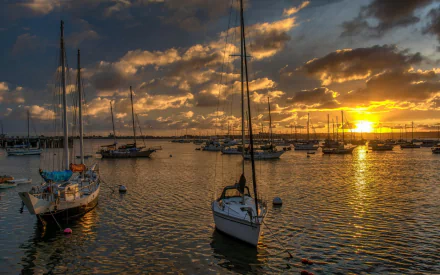 HD PC desktop wallpaper featuring boats anchored in calm water during a vibrant sunset, capturing a serene maritime scene with dramatic clouds and golden light.