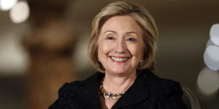 HD desktop wallpaper featuring Hillary Rodham Clinton smiling in a black outfit with a blurred background.