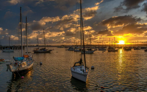 HD PC desktop wallpaper featuring boats anchored in calm water during a vibrant sunset, capturing a serene maritime scene with dramatic clouds and golden light.