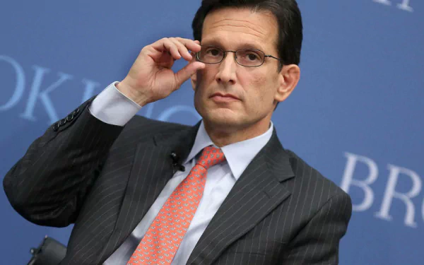 HD desktop wallpaper featuring a man in a suit adjusting his glasses against a blue background with BROOKINGS text.