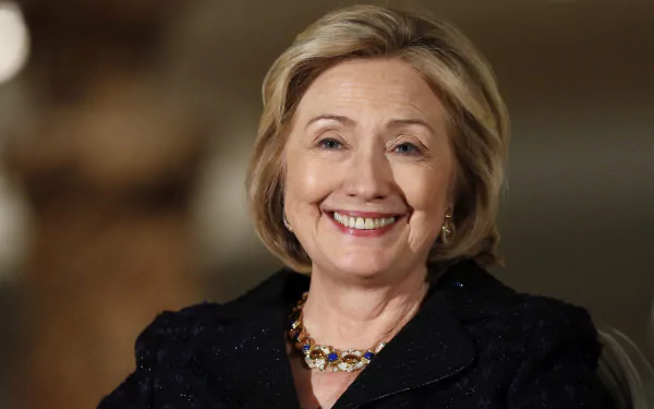 HD desktop wallpaper featuring Hillary Rodham Clinton smiling in a black outfit with a blurred background.