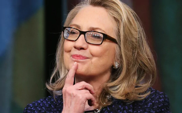 HD wallpaper of a smiling woman with glasses, touching her chin thoughtfully, set against a blurred background.