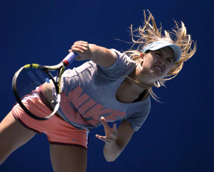 HD wallpaper featuring tennis player Eugenie Bouchard in action, captured mid-serve against a clear blue sky, showcasing dynamic sports energy.