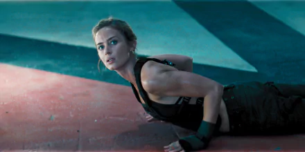 Emily Blunt in a scene from the movie Edge of Tomorrow, showcasing an intense moment as she navigates a challenging environment, set against a vibrant background. HD desktop wallpaper.