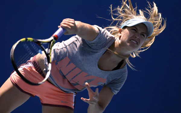 HD wallpaper featuring tennis player Eugenie Bouchard in action, captured mid-serve against a clear blue sky, showcasing dynamic sports energy.