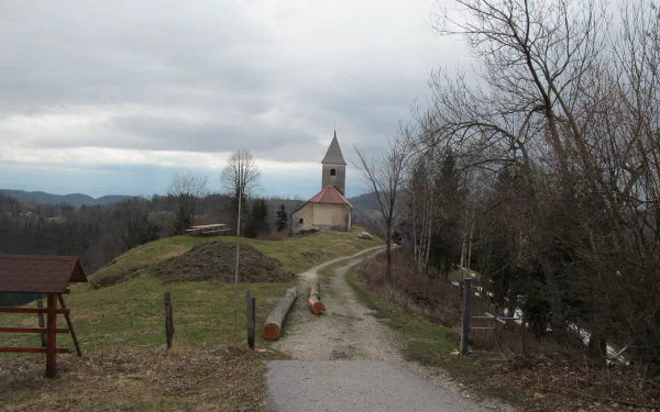Religious church on a hilltop along a winding path under overcast sky, bare trees and distant mountains — 4K Ultra HD PC Desktop Wallpaper and Background, serene rural landscape.