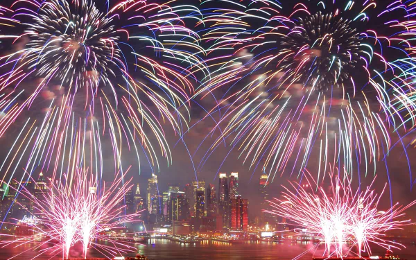 Vibrant fireworks display over a city skyline for a 4th of July celebration, used as an HD desktop wallpaper/background.