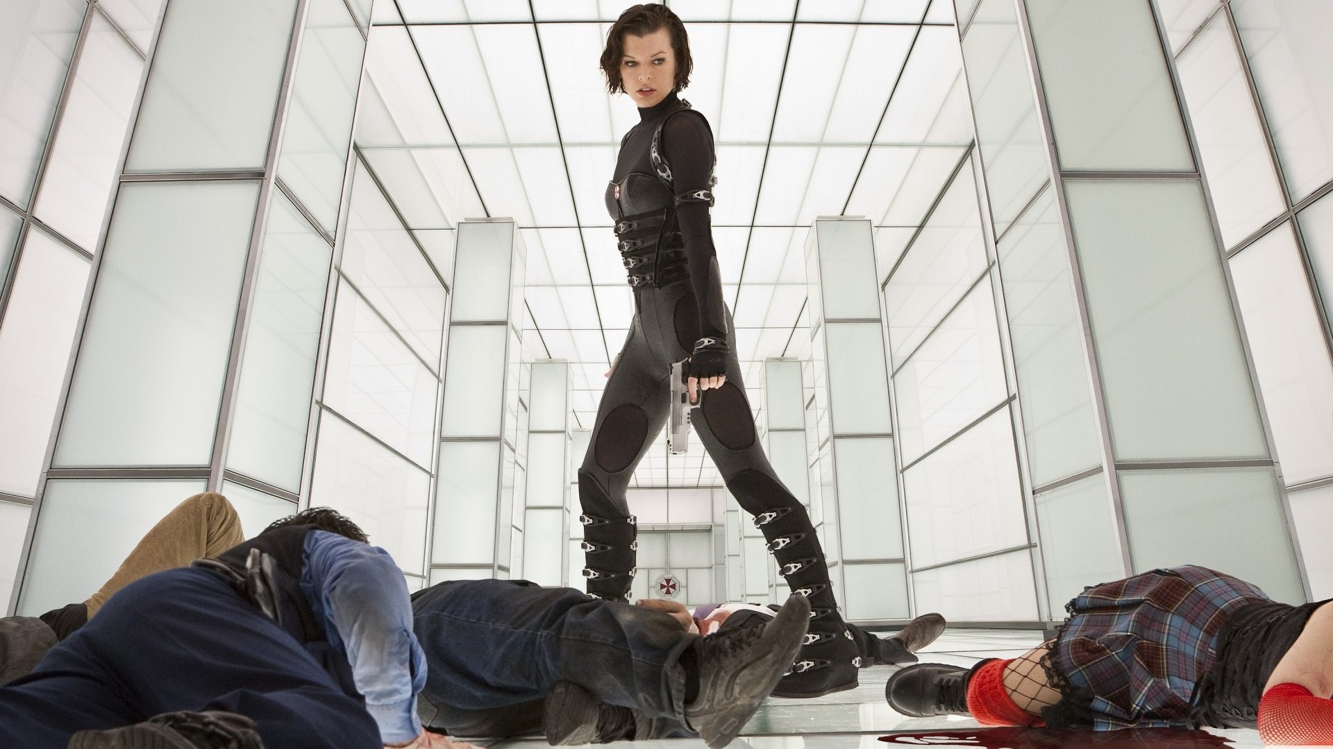 A scene from Resident Evil: Retribution featuring a confident warrior standing in a futuristic corridor, surrounded by defeated foes, set as a high-definition PC desktop wallpaper.
