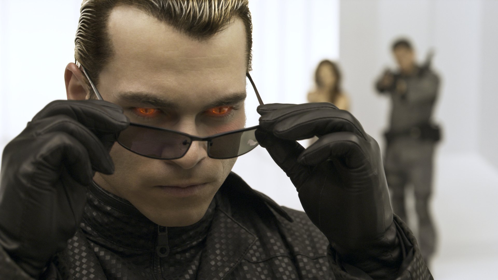 HD PC desktop wallpaper featuring a close-up of a character with glowing red eyes from the movie Resident Evil: Afterlife, with two blurred figures in the background.