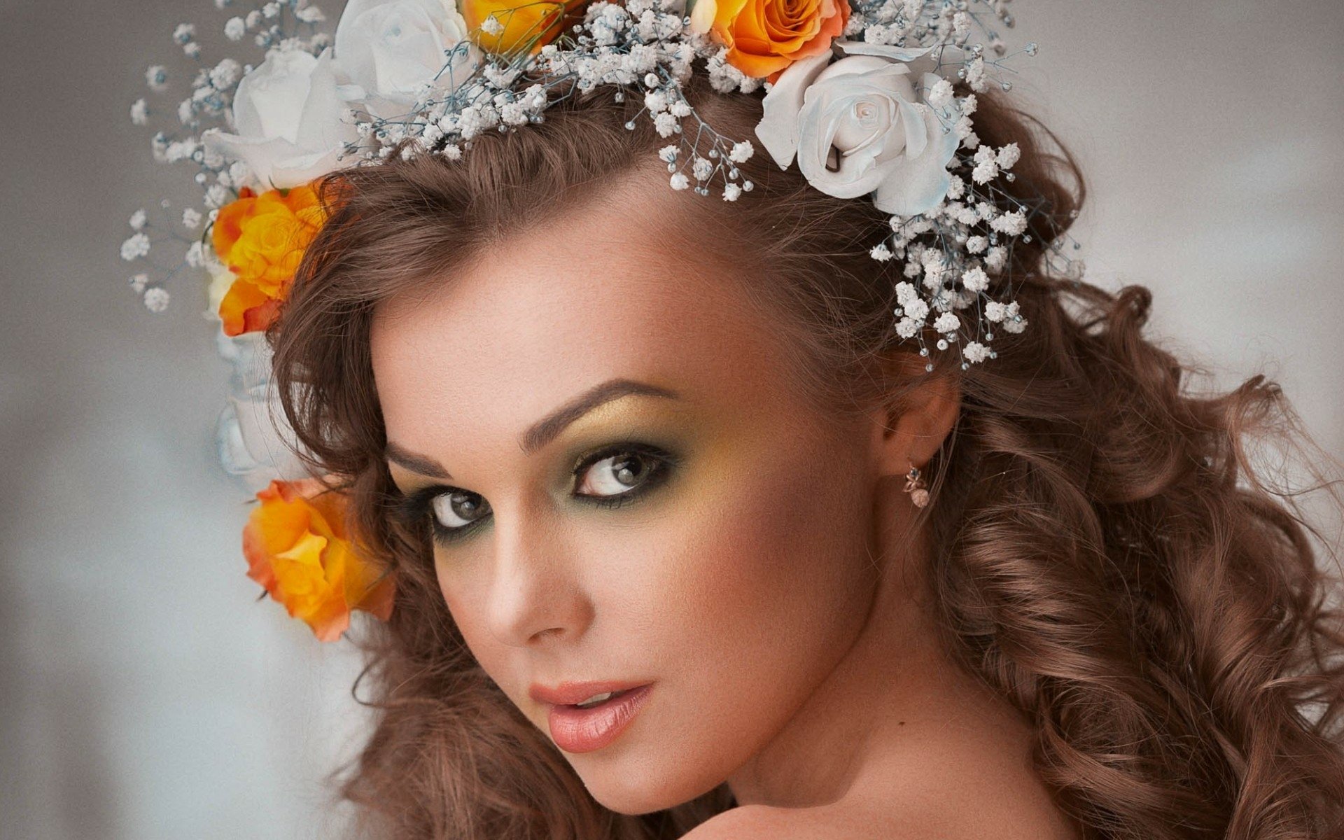 HD desktop wallpaper featuring a woman with curly hair adorned with a floral crown of white and yellow flowers, gazing over her shoulder.