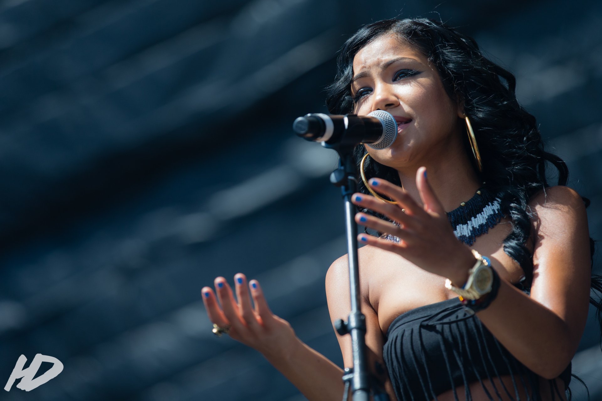 HD desktop wallpaper featuring Jhené Aiko singing into a microphone with an expressive gesture, set against a blurred background.
