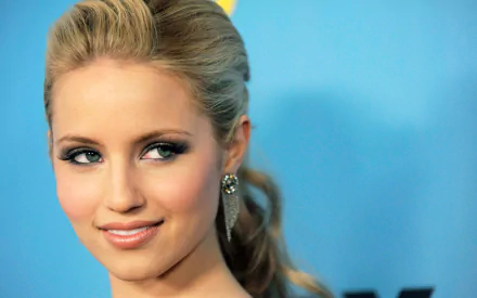 Close-up portrait of an American actress and celebrity with blonde swept-back hair and a soft smile against a blue backdrop — 2K Quad HD PC desktop wallpaper.