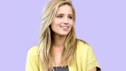 HD PC desktop wallpaper of a smiling American actress and celebrity with long blonde hair wearing a yellow top against a soft lavender background.