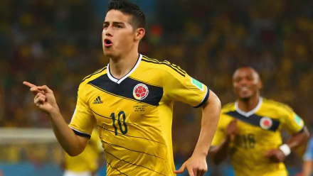 HD wallpaper of a soccer player in yellow Colombia kit in action on the field, energetic background for desktops.