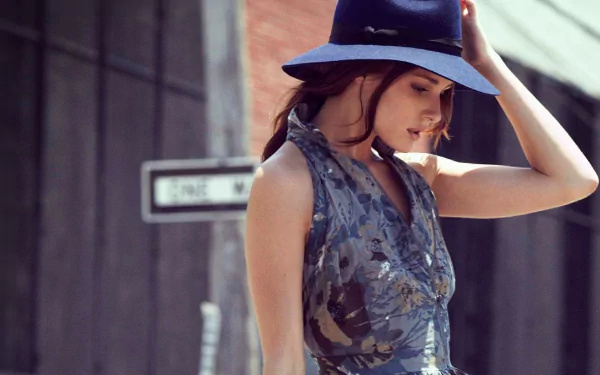 A stylish woman, Olivia Palermo, wears a blue hat and a floral dress, gazing down as she poses outdoors, creating a chic HD desktop wallpaper and background.