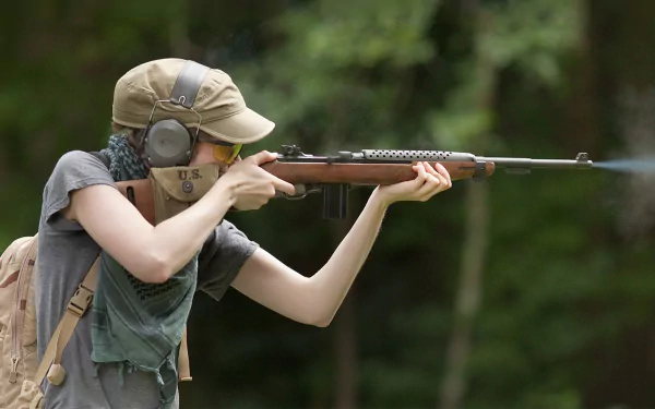 HD PC desktop wallpaper: person in cap and ear protection aiming a man-made rifle against a blurred forest background.
