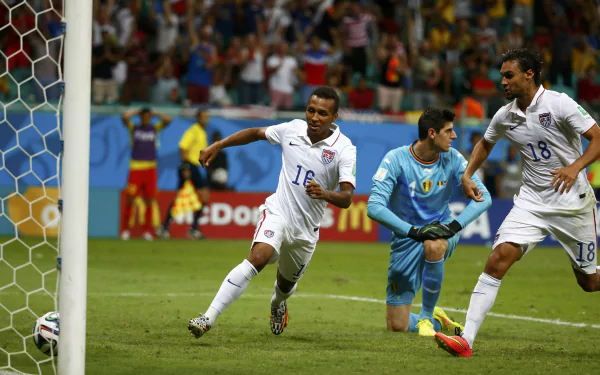 HD wallpaper of a soccer match with a player chasing the ball near the goal post, with spectators in the background.
