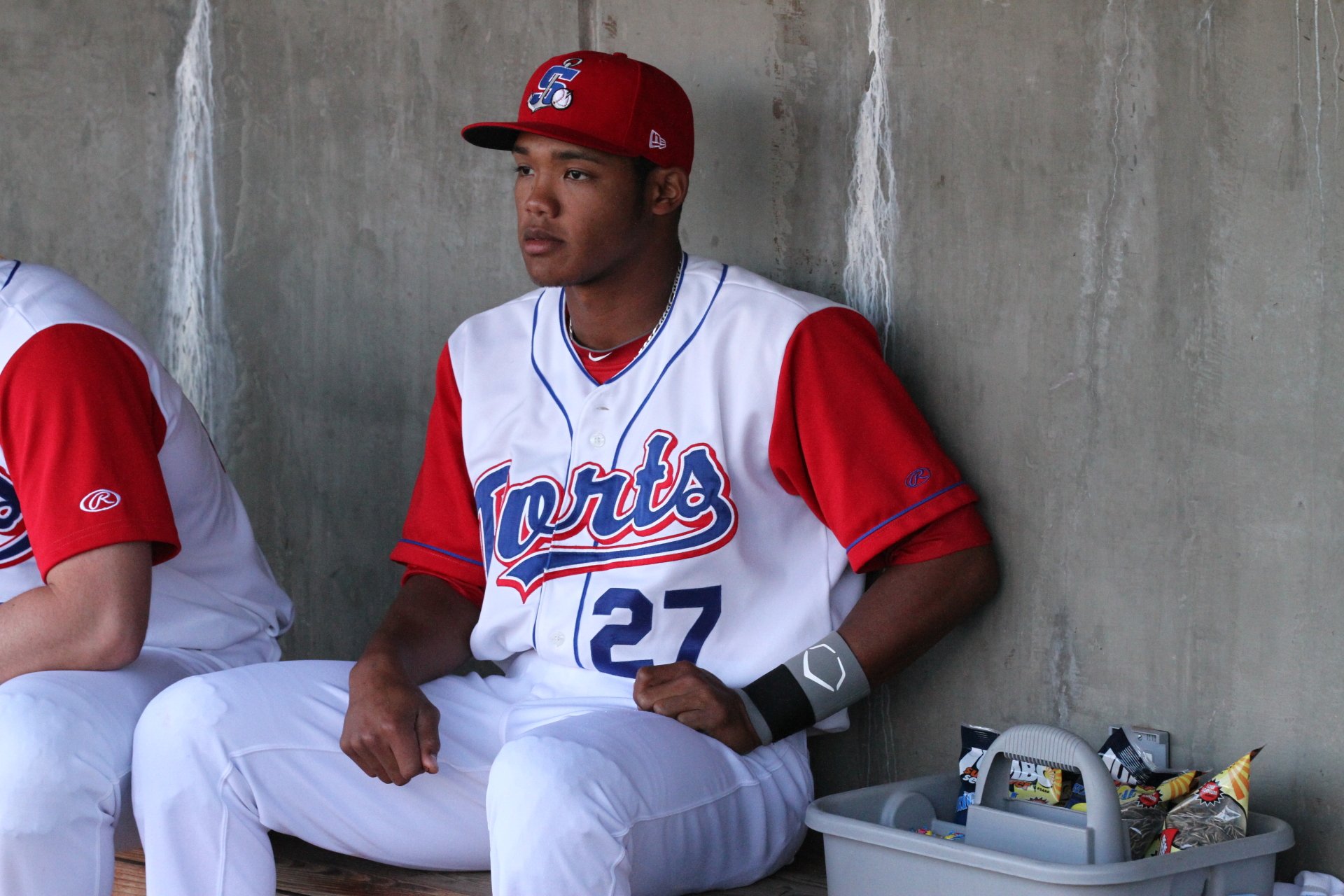 HD wallpaper of a baseball player in red and white uniform, number 27, sitting in the dugout.