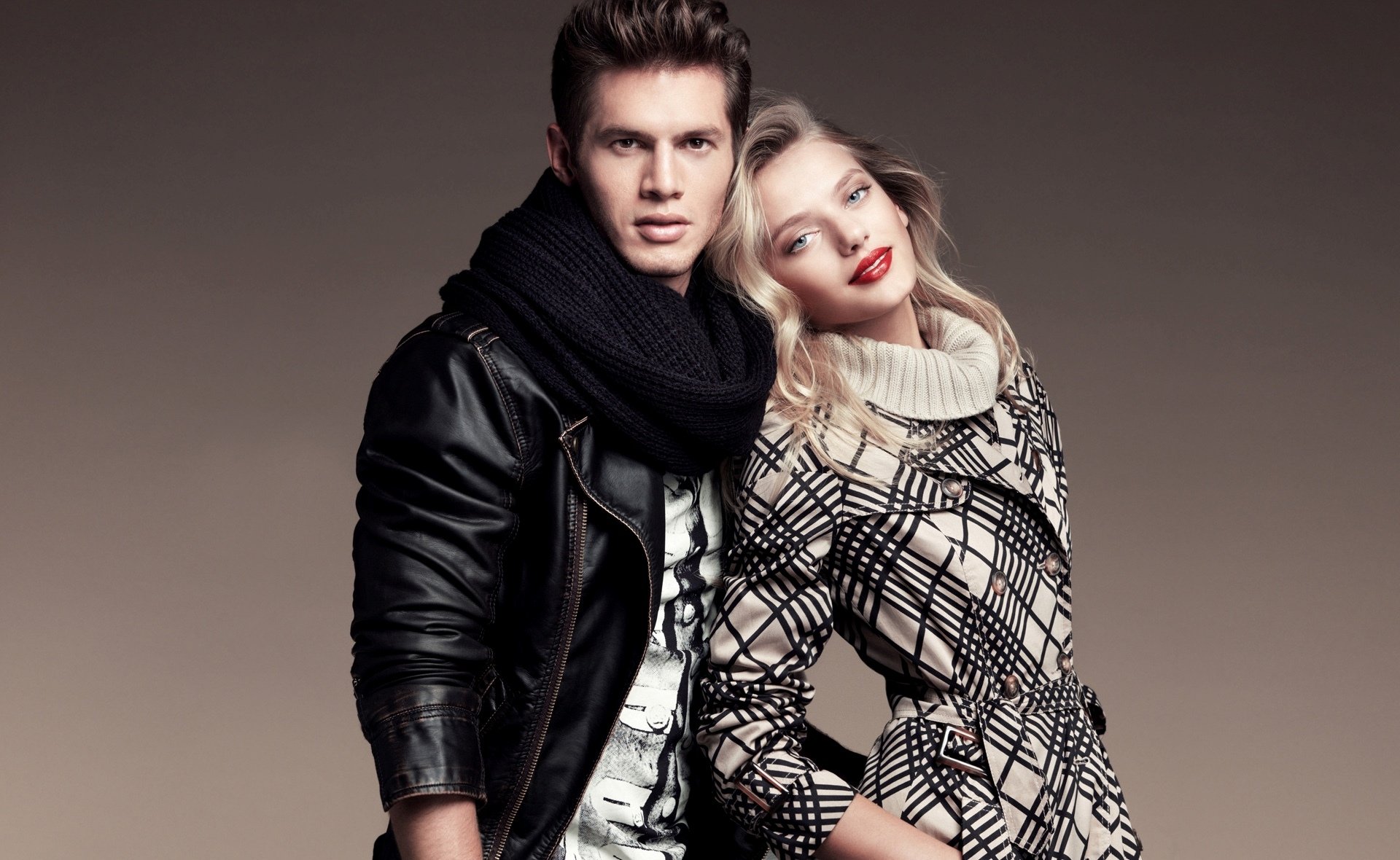 HD PC desktop wallpaper of a Dutch female model posing with a male model; she leans on him in a patterned dress while he wears a leather jacket and scarf.