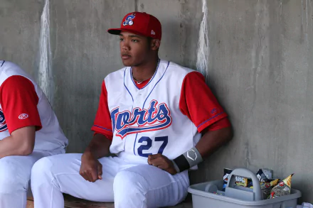 HD wallpaper of a baseball player in red and white uniform, number 27, sitting in the dugout.