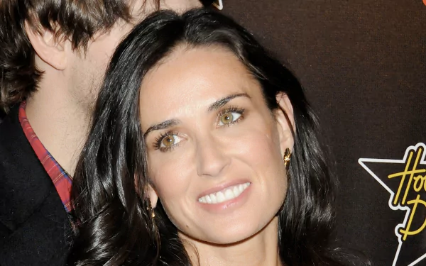 HD desktop wallpaper featuring American actress and celebrity Demi Moore with a warm smile and dark hair against a dark background.