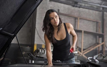 High-definition desktop wallpaper of Michelle Rodriguez as Letty Ortiz in the movie Fast & Furious 6, showing her working on a car in a garage setting.