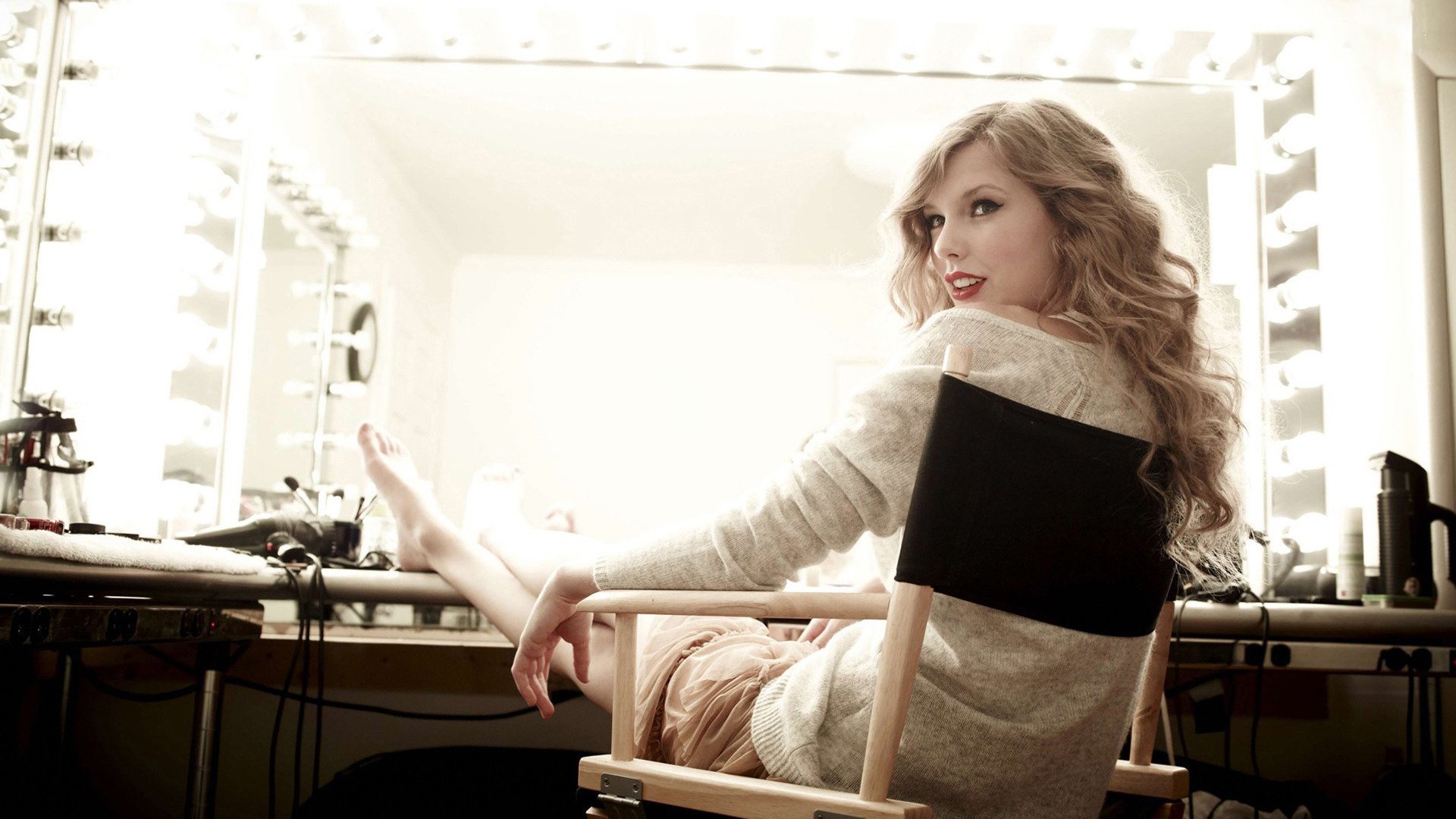 HD PC desktop wallpaper of a female singer sitting in a dressing-room director's chair, backlit vanity mirrors and a warm, music-themed atmosphere.