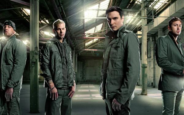 A high-definition wallpaper featuring the band Breaking Benjamin standing confidently in an industrial setting, illuminated by dramatic lighting.