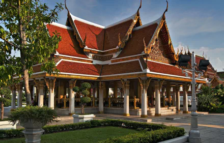 HD PC desktop wallpaper and background of a religious temple in Thailand, featuring ornate red-and-gold roofs, white columns, manicured gardens and a clear blue sky.