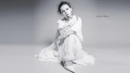Black and white HD desktop wallpaper featuring American actress and celebrity Nicola Peltz in a thoughtful pose, dressed in flowing white attire.