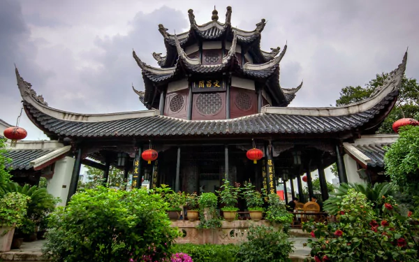 HD desktop wallpaper of a Chinese religious temple: ornate multi-tiered pagoda roof, red lanterns and lush gardens beneath a moody sky.