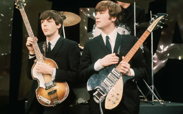An ultra HD wallpaper featuring members of The Beatles performing, with Paul McCartney on bass and John Lennon holding an electric guitar, capturing the essence of iconic music history.