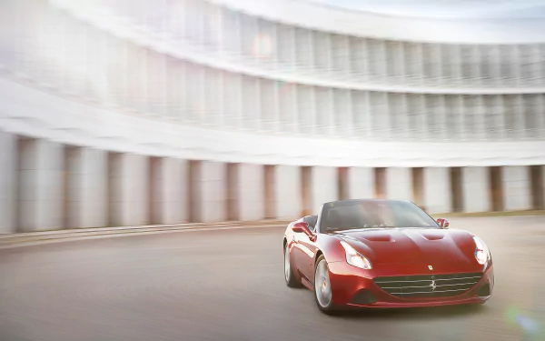 Red Ferrari California T racing past a curved colonnade with motion blur — 2K Quad HD PC desktop wallpaper of the vehicle.