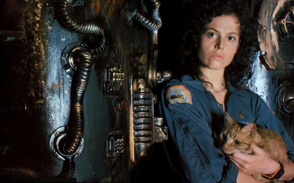 A character from the movie Alien stands confidently against a metallic backdrop, holding a cat. The image serves as a striking HD desktop wallpaper and background.