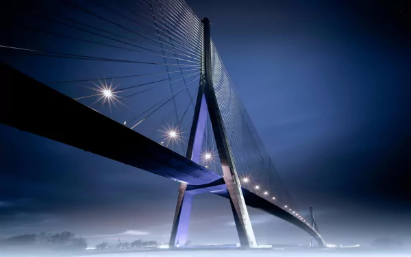 HD desktop wallpaper of the Pont de Normandie, a striking man-made cable-stayed bridge illuminated against a deep blue evening sky.