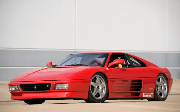HD desktop wallpaper: red Ferrari 348 GT Competizione vehicle parked on sunlit pavement, three-quarter front view showcasing sleek lines and alloy wheels.