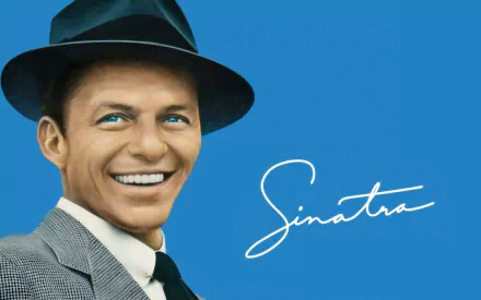 HD PC desktop wallpaper of a smiling male crooner in a suit and fedora on a bright blue background, accented by a flowing white cursive signature and a music-themed mood.
